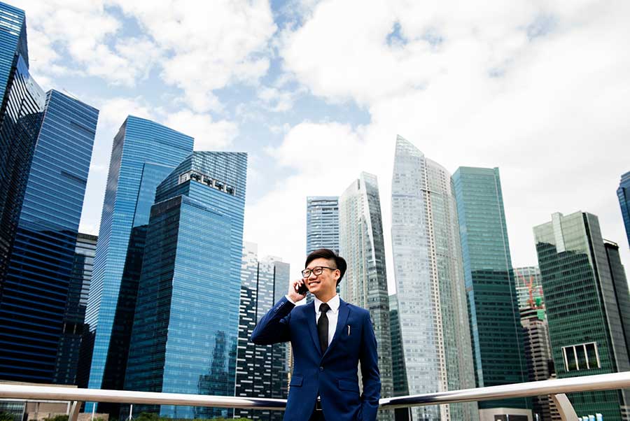 Asian businessman one the phone in front of buildings